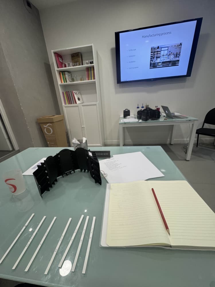 Table de travail en cours de parfumerie : mouillettes annotées, carnet, et une diapositive sur les procédés d’extraction.